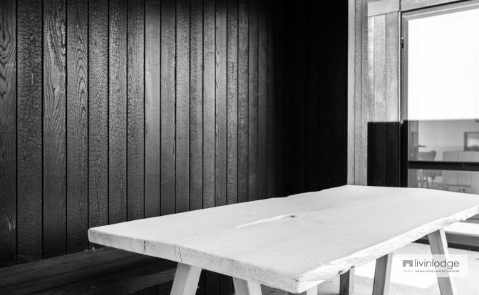 Witte houten tafel onder zwarte terrasoverkapping in gebrand hout